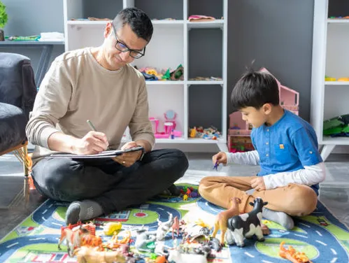 Male therapist with young boy in blue shirt