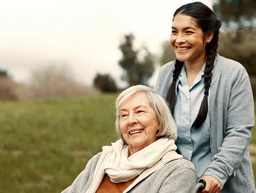 Caregiver pushing an elderly woman in a wheelchair 