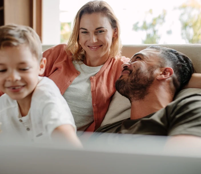 Happy young family relaxing on couch at home.