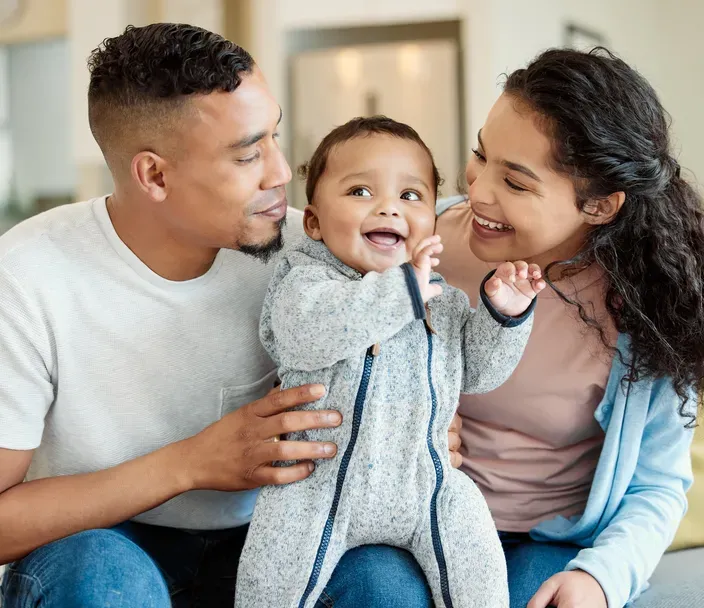 A young couple hugging their toddler