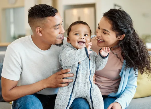 A young couple hugging their toddler