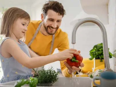 Dad and daughter washing vegetables in kitchen