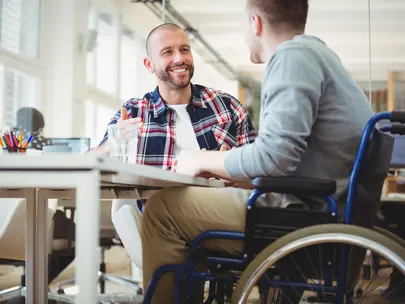 Person in wheelchair talking with friend in office space